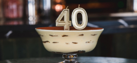 A tiramisu cake in a glass bowl with number 40 candle on top