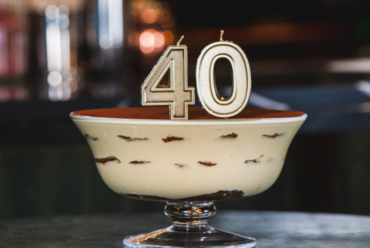 A tiramisu cake in a glass bowl with number 40 candle on top