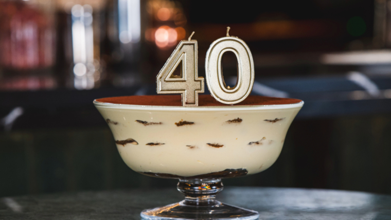 A tiramisu cake in a glass bowl with number 40 candle on top