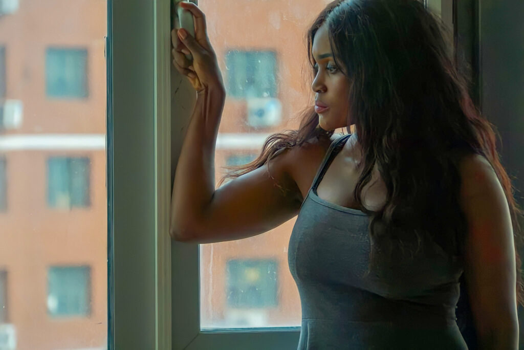 Woman standing by the window looking pensive.