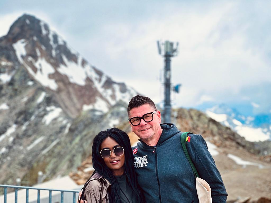 Multiracial couple posing for a photo in front of a glacier mountain