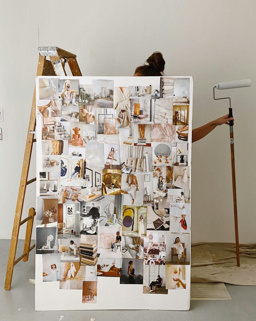 A woman stands behind a large vision board covered in various outfit images