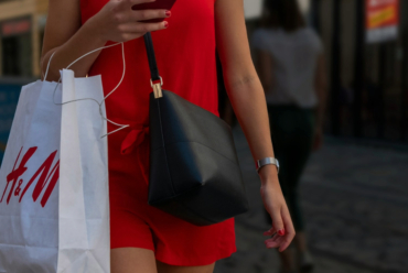 A woman walking and carrying a shopping bag after shopping trip alone