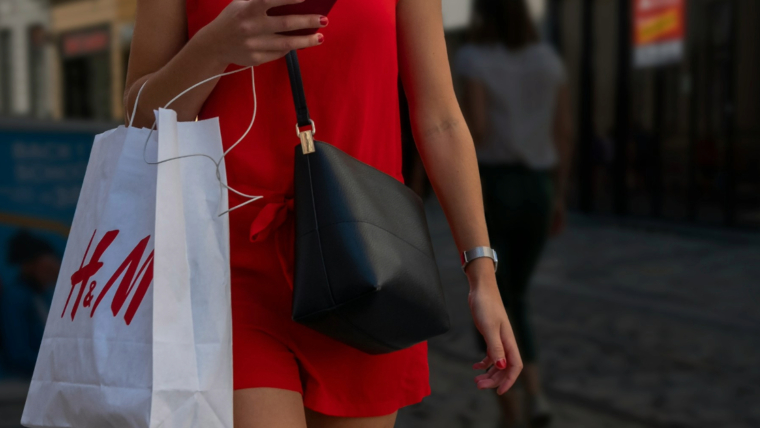 A woman walking and carrying a shopping bag after shopping trip alone