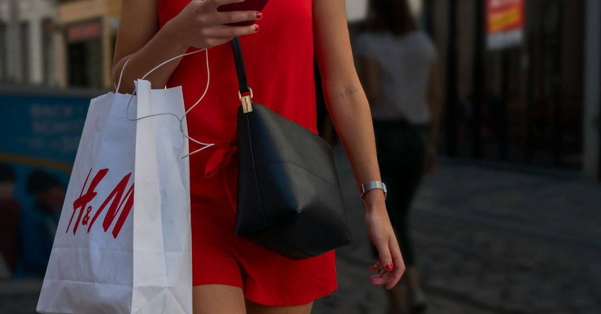 A woman walking and carrying a shopping bag after shopping trip alone