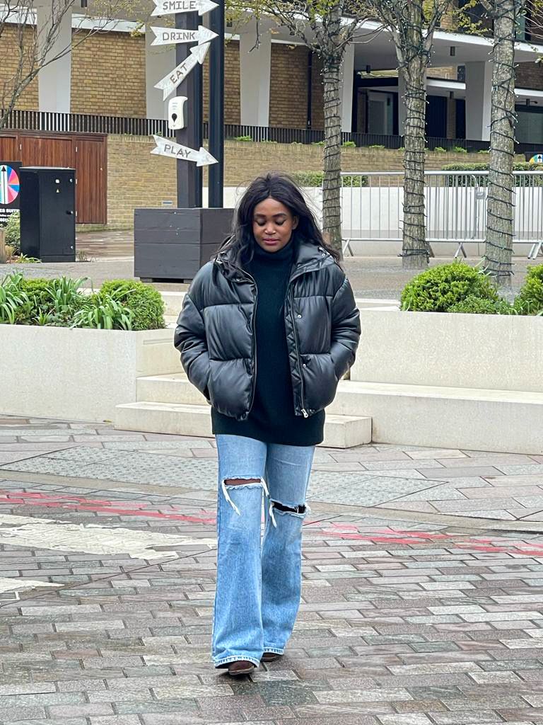 Woman with black puffer jacket and ripped blue jeans