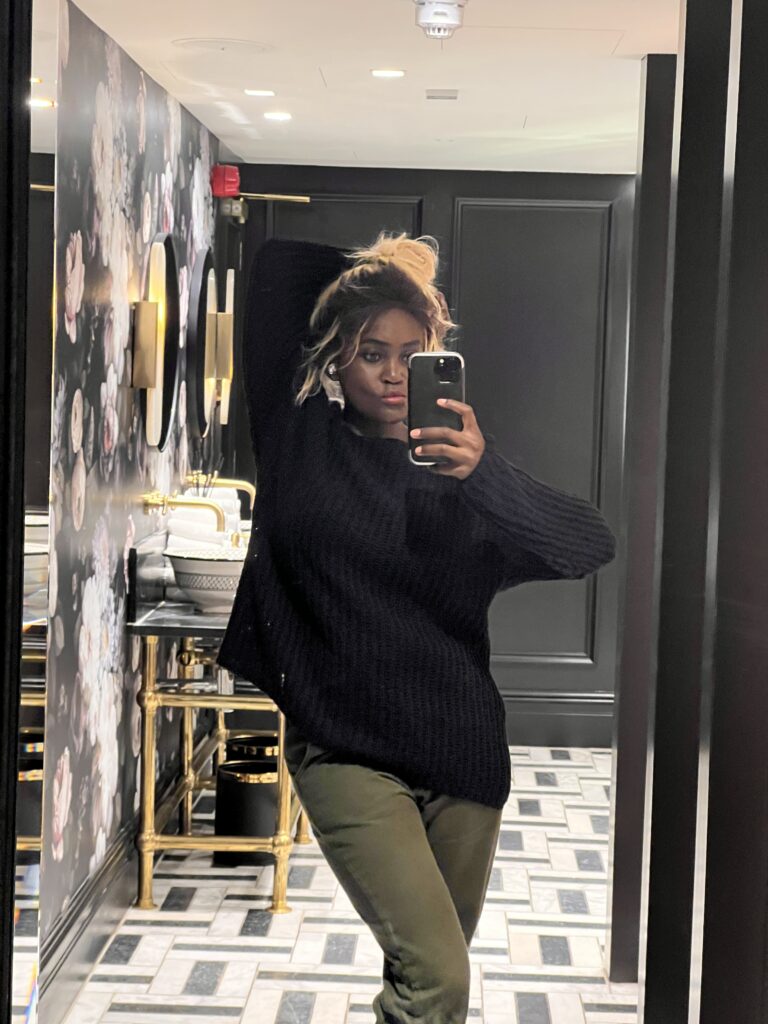 Woman wearing stylish green denim  jeans taking a selfie in a colourful bathroom