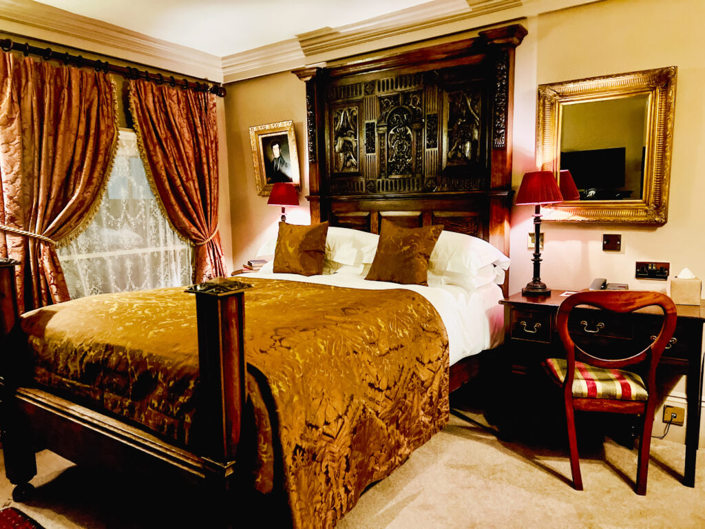A meticulously designed hotel room. The space exudes sophistication with a tasteful combination of brown wall decor and plush bedding, creating an atmosphere of refined elegance. A functional desk and chair enhance your comfort, while an artful wall painting above the headboard adds a touch of captivating charm.