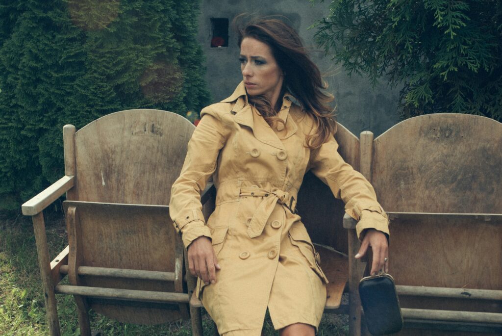 Stylish woman in classic trench coat sits gracefully on a rustic bench, exuding timeless elegance and sophistication