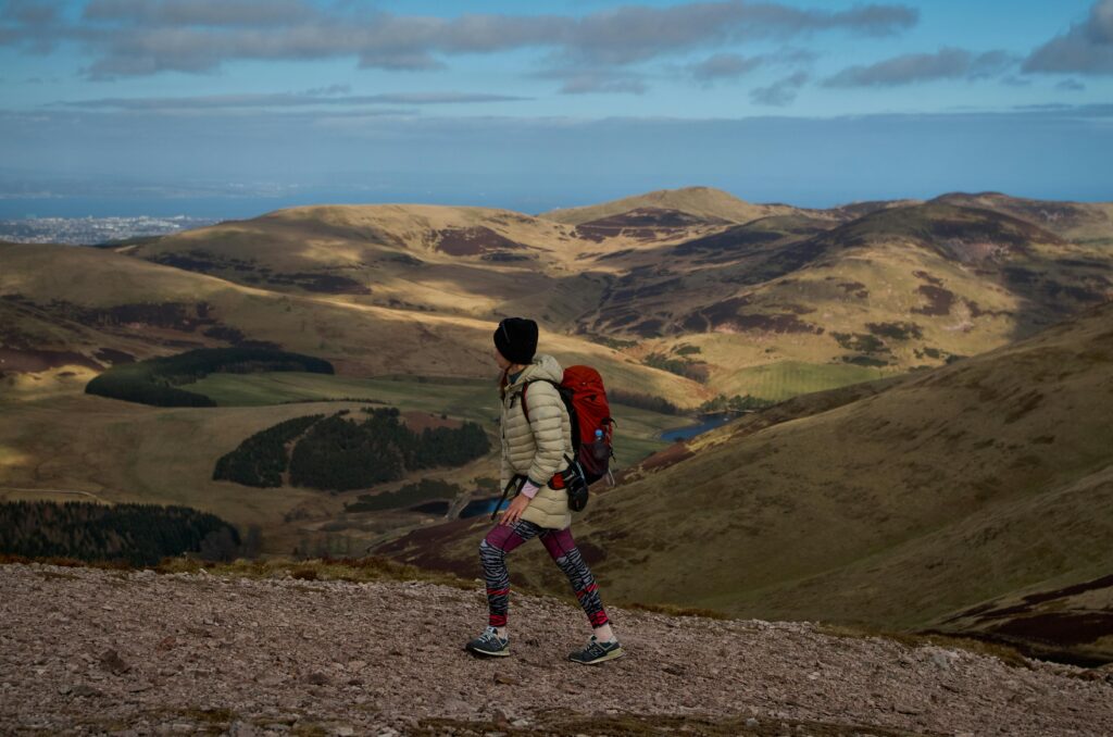 Woman with a red backpack hiking alone in the mountains