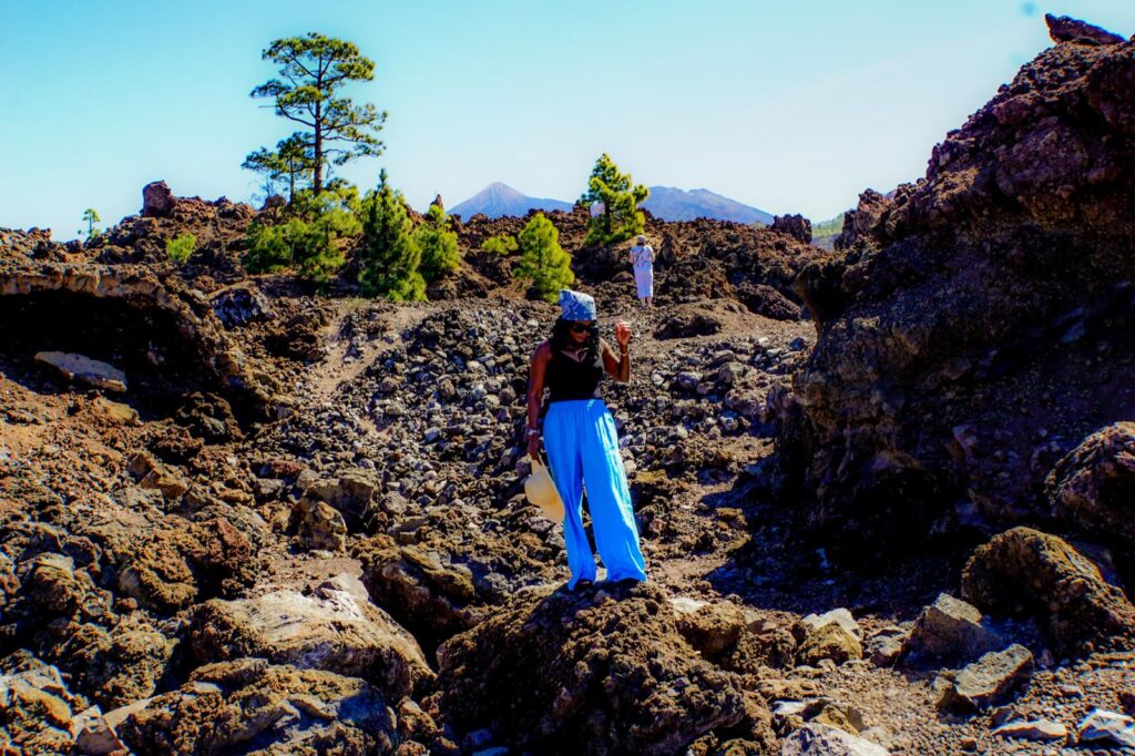Woman exploring volcanic landscape in Tenerife's Teide National Park with mountain views in the background.