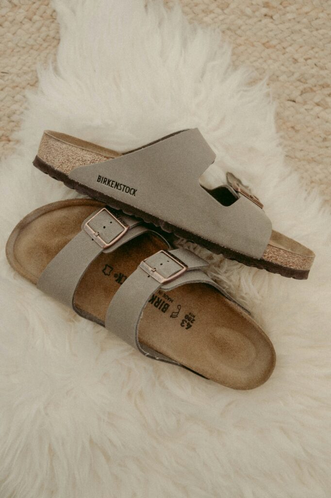 A pair of brown sandals on sand.
