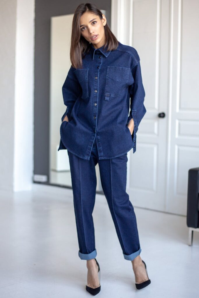 Woman in a matching oversized denim shirt and trousers with rolled-up hems and black heels