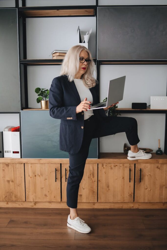 A woman in a stylish power suit paired with white sneakers, standing confidently in an office