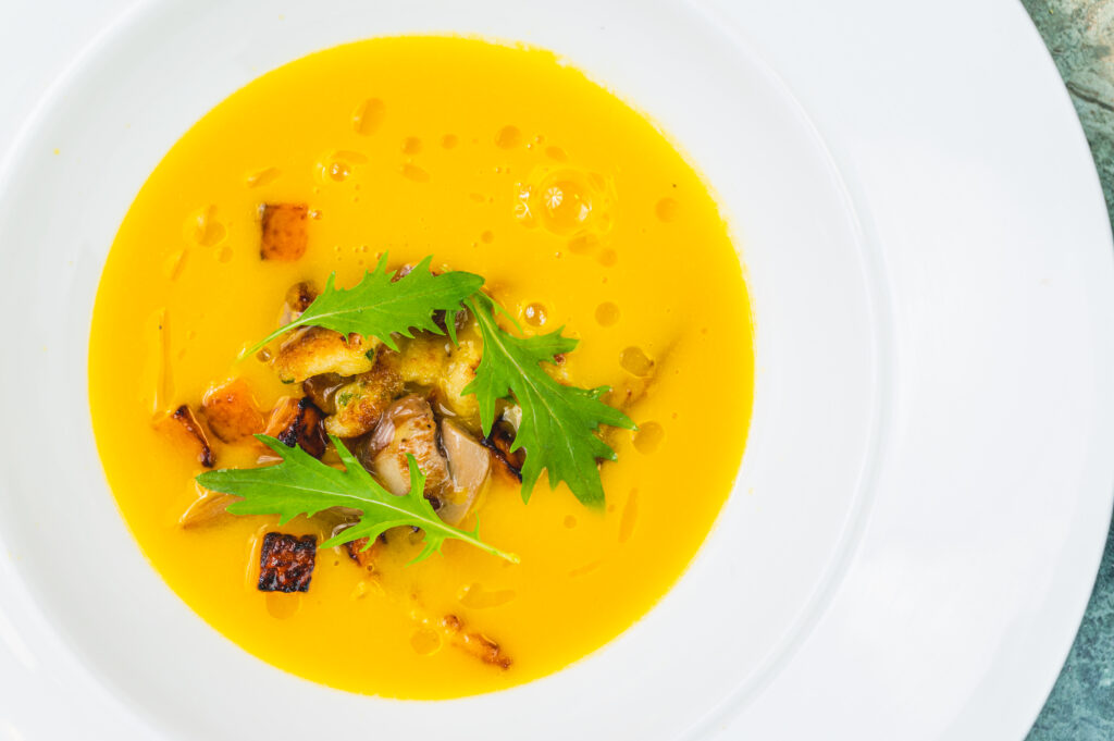 Pumpkin soup, garnished with mushrooms and rocket leaves.