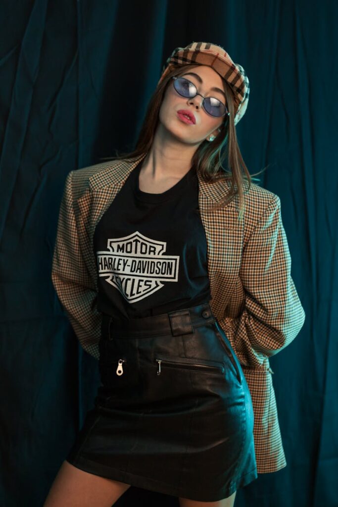 Woman in a Harley-Davidson t-shirt, leather skirt, oversized blazer, and checkered cap