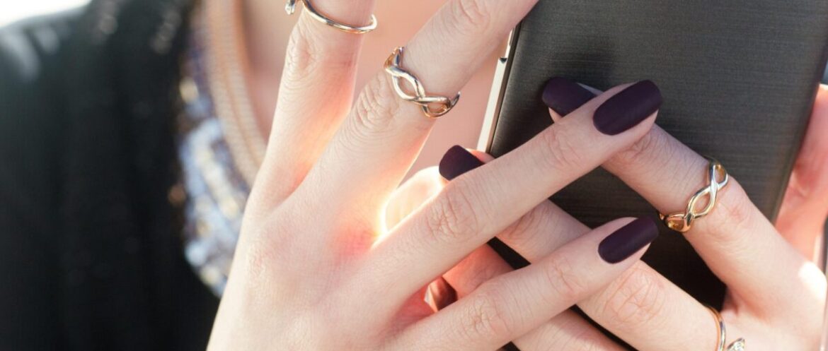 person with black nail polish holding a phone