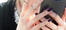 person with black nail polish holding a phone