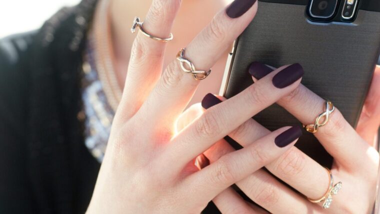 person with black nail polish holding a phone