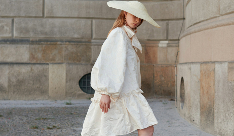 Woman in a white loose dress and matching wide brim hat - a stylish summer outfit