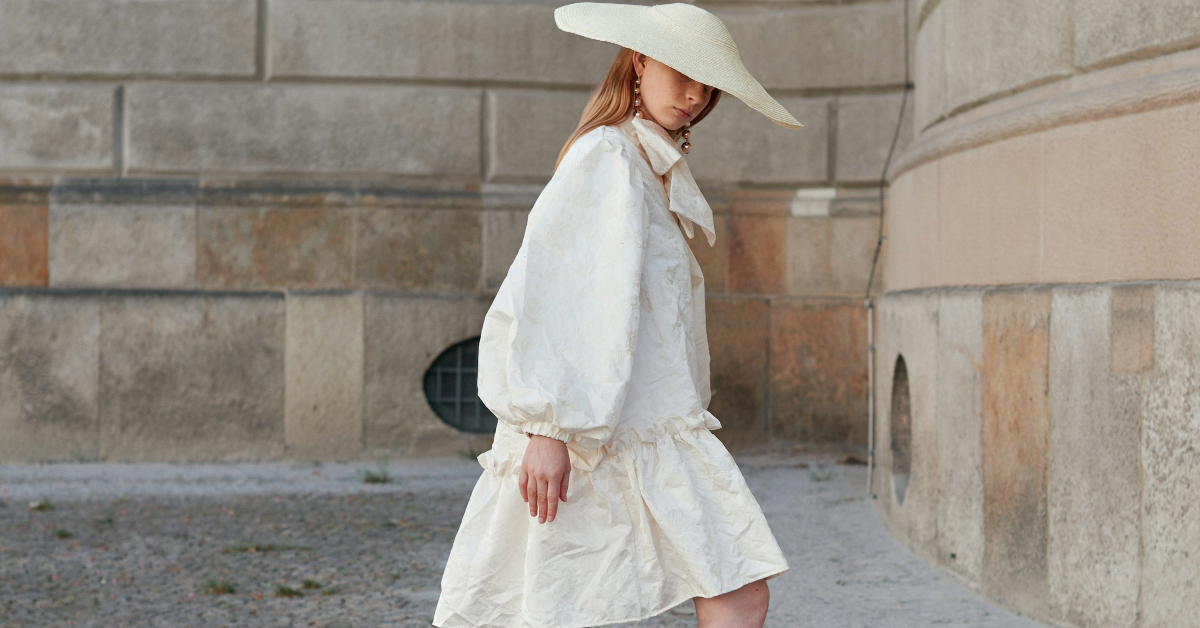 Woman in a white loose dress and matching wide brim hat - a stylish summer outfit