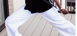 Close-up of a woman's legs in white wide-leg pants on a light wooden floor.