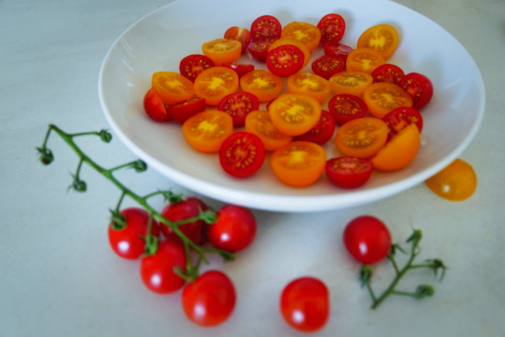 Fresh cherry tomatoes sliced for Burrata Caprese salad – a simple, vibrant base for a classic Italian summer dish.