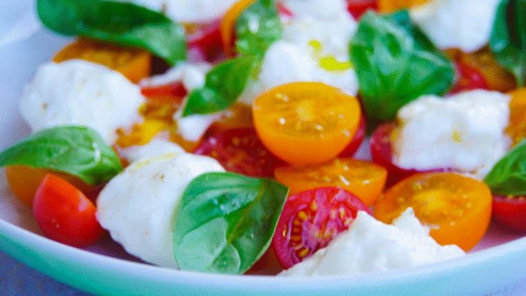 Close-up of Burrata Caprese made with creamy burrata, halved cherry tomatoes, and balsamic glaze. An easy no-cook Italian summer recipe.