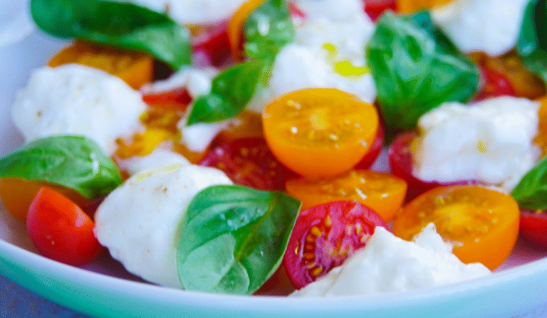 Close-up of Burrata Caprese made with creamy burrata, halved cherry tomatoes, and balsamic glaze. An easy no-cook Italian summer recipe.
