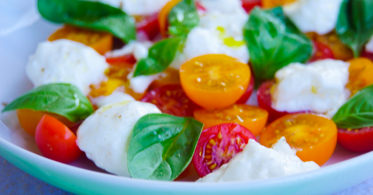 Close-up of Burrata Caprese made with creamy burrata, halved cherry tomatoes, and balsamic glaze. An easy no-cook Italian summer recipe.