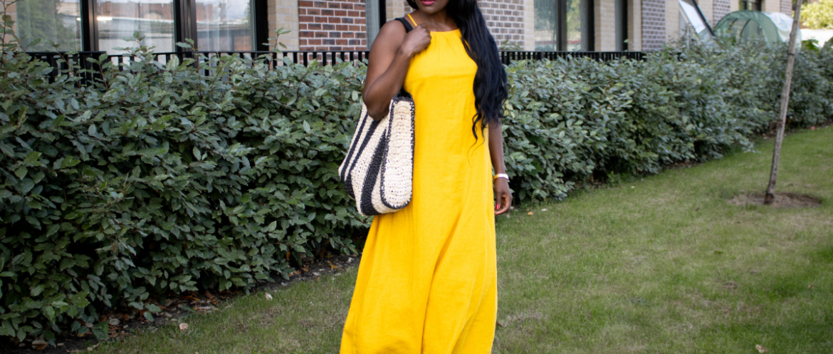 What to wear in Sub-Saharan Africa in July and August – woman in sunglasses wearing a yolk yellow linen dress over wide-leg blue jeans