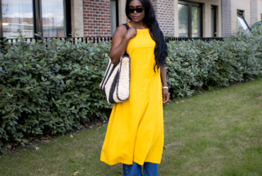 What to wear in Sub-Saharan Africa in July and August – woman in sunglasses wearing a yolk yellow linen dress over wide-leg blue jeans