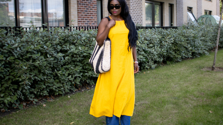 What to wear in Sub-Saharan Africa in July and August – woman in sunglasses wearing a yolk yellow linen dress over wide-leg blue jeans