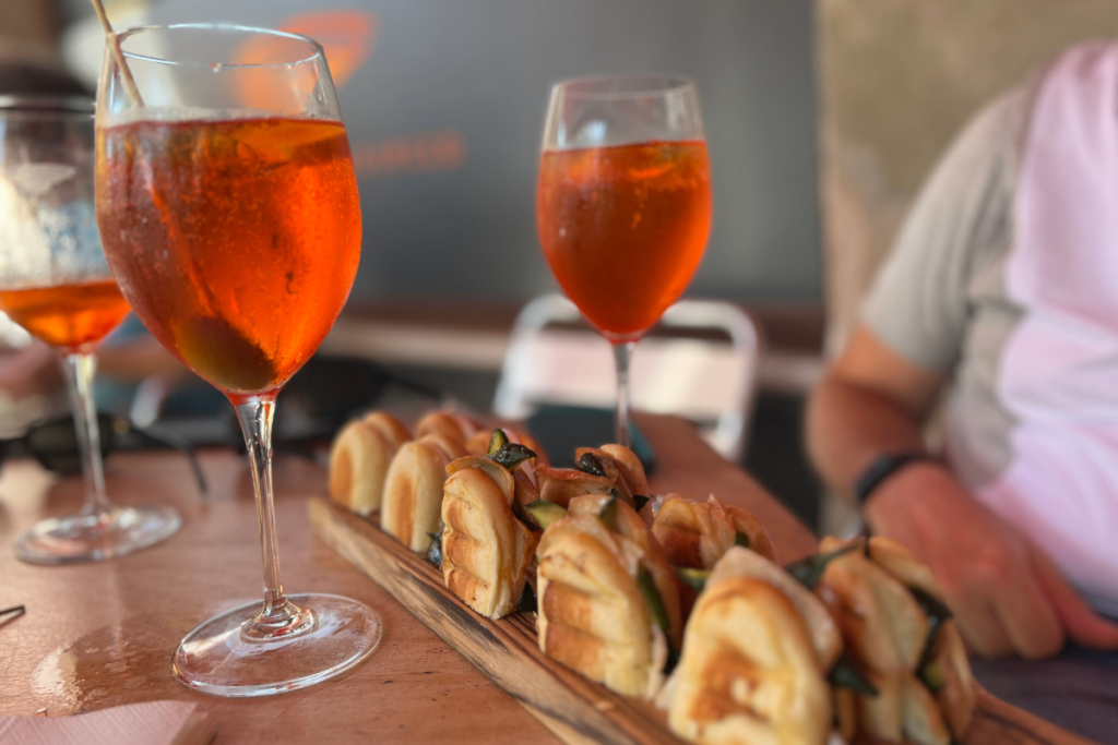 A close-up of cicchetti and Aperol Spritz on a wooden table at a Venetian bàcaro, capturing the flavour of slow travel and the question: Is Venice worth visiting in 2025?