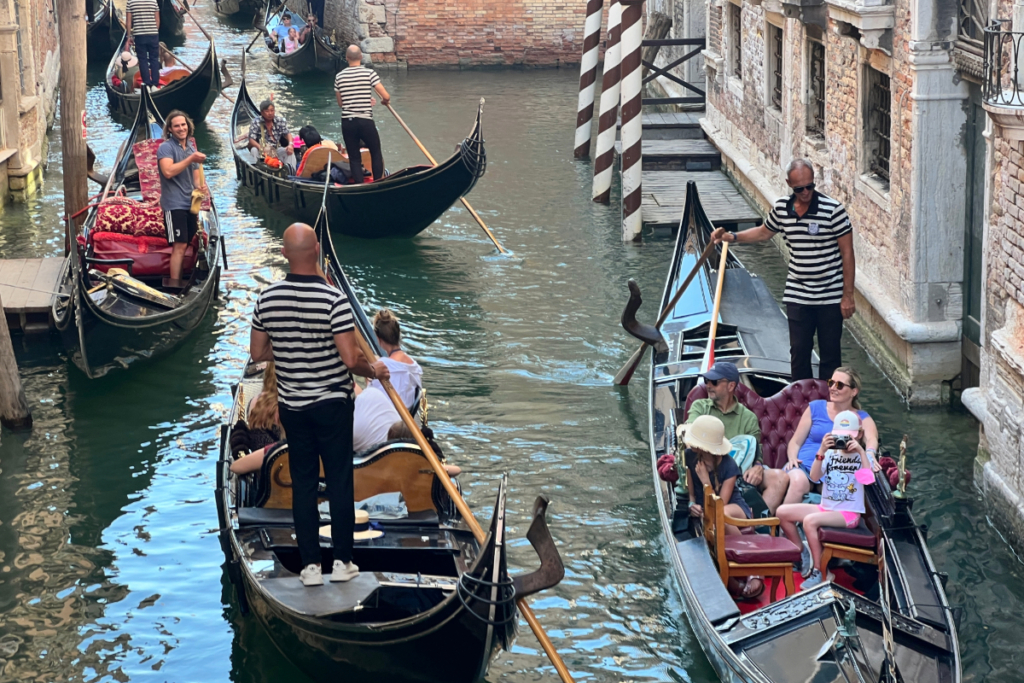 Is visiting Venice worth it: Multiple gondolas with gondoliers and tourists in a narrow Venice canal.