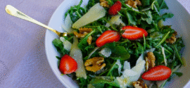 Fresh rocket salad with Parmesan salad and walnuts, served in a wide white bowl