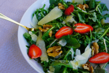 Fresh rocket salad with Parmesan salad and walnuts, served in a wide white bowl