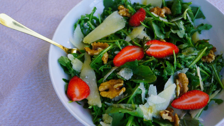 Fresh rocket salad with Parmesan salad and walnuts, served in a wide white bowl