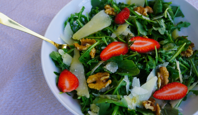 Fresh rocket salad with Parmesan salad and walnuts, served in a wide white bowl