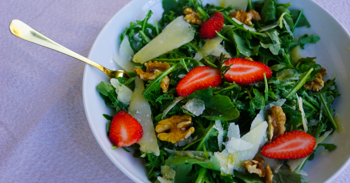 Fresh rocket salad with Parmesan salad and walnuts, served in a wide white bowl