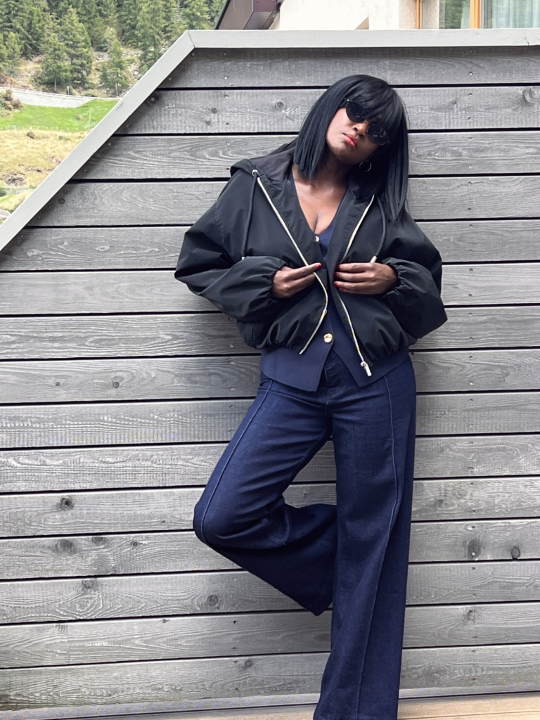 Woman styling dark-wash denim trousers with a black zip jacket, an essential look for an autumn capsule wardrobe.