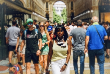 Woman walking through a busy Milan arcade surrounded by summer crowds, reflecting on the shift toward second city travel.