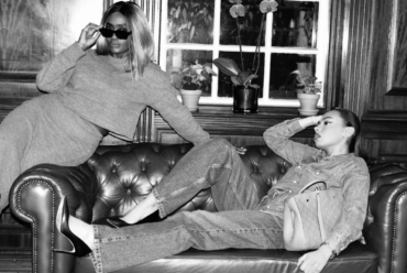 Two stylish women lounging on a leather sofa during a winter style slump, wearing layered knitwear, denim and sunglasses in a black-and-white London setting.