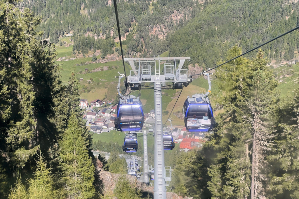 Cable car gondolas above Sölden village with forest and mountains in the background