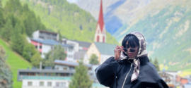Woman standing on balcony in Sölden with Alpine village and mountains in the background