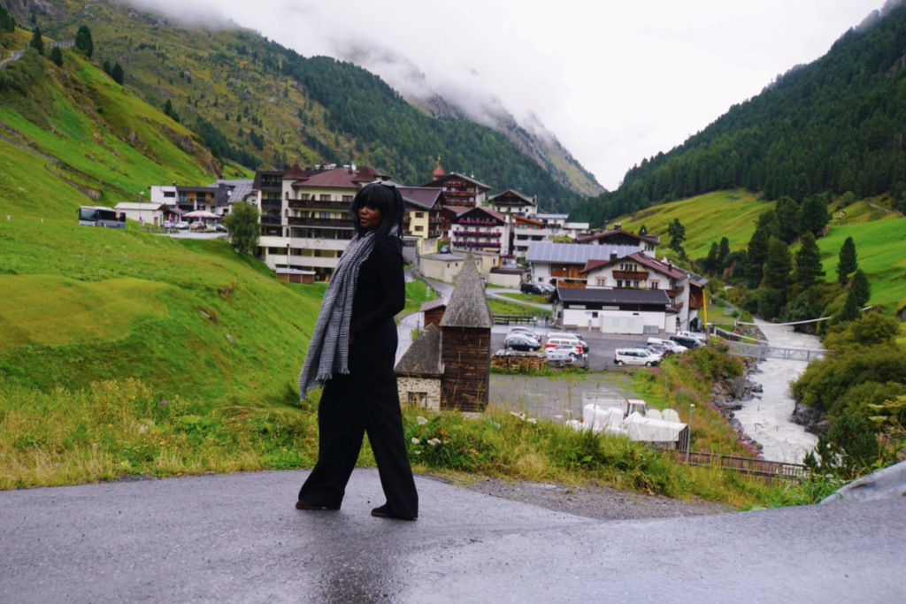 Woman standing on road in Alpine village near Sölden with mountains and river in the background