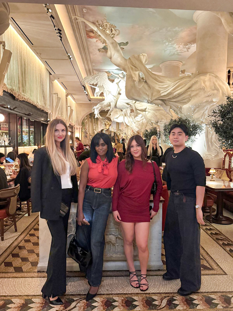 Four friends at Bacchanalia restaurant in Mayfair, London, posing beneath the dramatic white sculptures in the dining room.